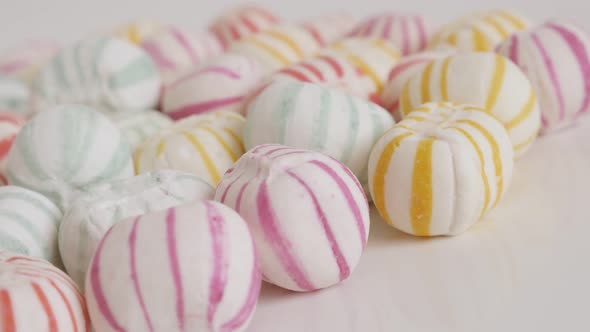 Pile of striped sugar bonbons on white close-up 4K video alt