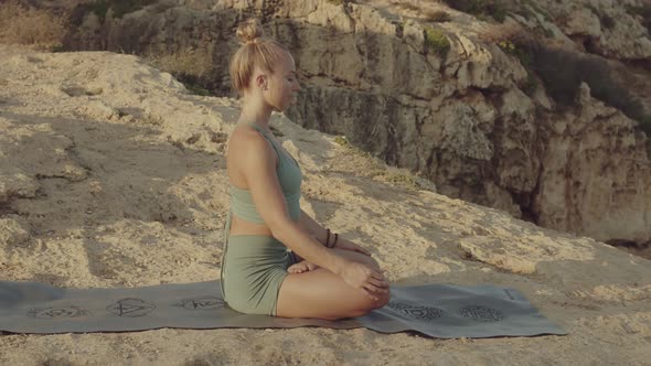 Blond Young Caucasian Female Yoga Teacher Meditating in the Mountains Near the Sea