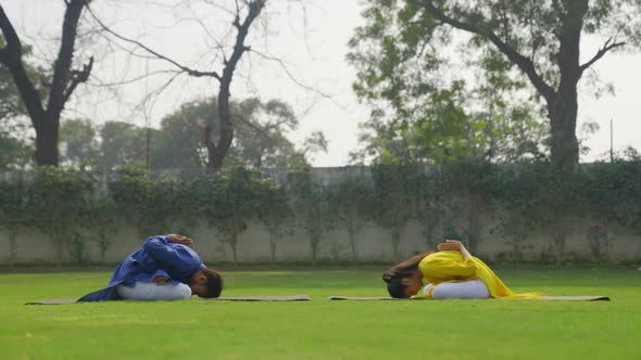 Padmasana with forward bend Yoga is being done by an Indian couple in an Indian outfit alt