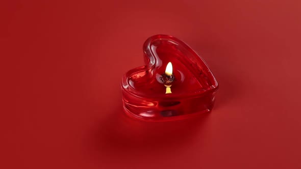 One heart shaped candles burning and rotating on red background