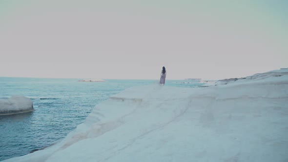 Woman Walks Along the Coastline on the Rocks
