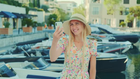 Smiling Young Lady Standing in Yacht Port and Making Video Call By Smartphone
