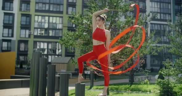 Young Woman in Red Performs Callisthenics with Ribbon in the Libing Apartment Yard, Gymnast Does alt