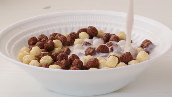 Milk Pouring Into a Bowl with Chocolate Balls Cereals for Breakfast