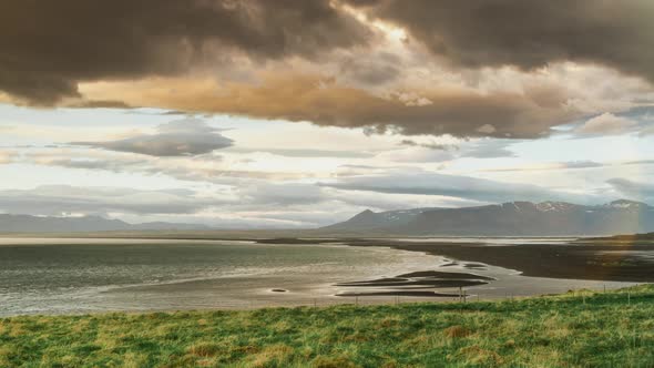 Rolling Clouds In Yellow Sunset Light Over Nothern Snow Mountains And Arctic Sea Waves In Iceland