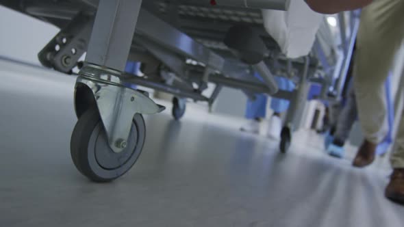Feet of doctors walking through corridor transporting patient in bed on wheels alt