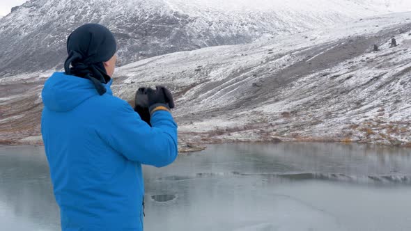 A Man Stands on a High Point in the Mountains and Admires a Beautiful View. There Are Peaks Around alt
