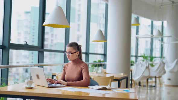 Beautiful business woman wearing light brown blouse working on her laptop alt