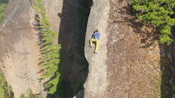 Aerial Shot of a Young Man Carefully Climbing a Rock Wall Without a Safety Net