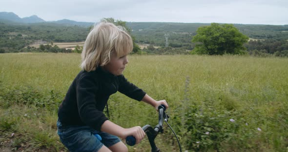 Cute Happy Child Boy Rides Bike on Country Road