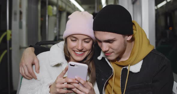 Crop View of Millennial Couple Looking at Smartphone Screen While Watching Video and Smiling alt