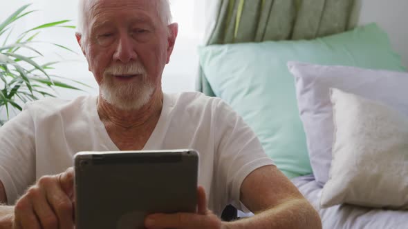 Senior man in social distancing using digital tablet alt