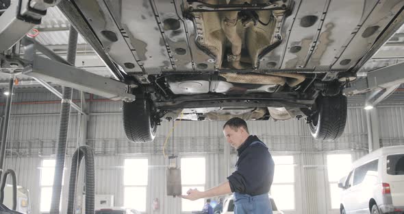 Tired Mechanic Draining Old Brake Fluid From A System. Auto Service alt
