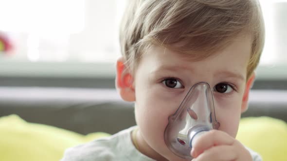 Close Up Caucasian 34 Years Minor Preschool Boy Kid in the Mask of an Inhaler on Yellow Gray Sofa alt