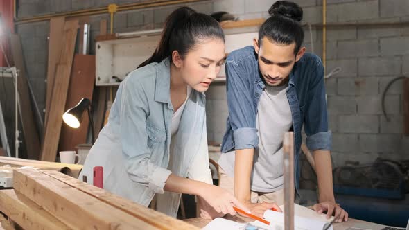 Young Asian couple carpenters man and woman discussing about design of products on laptop.