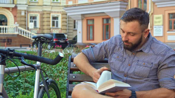 Cyclist Turns the Page of the Book on the Bench alt