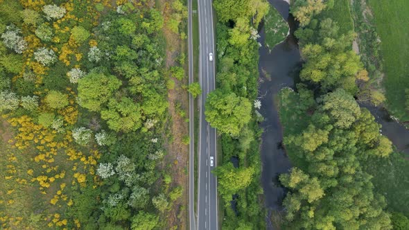 Two cars following each other through a lush and leafy landscape during spring in Europe. Static aer alt