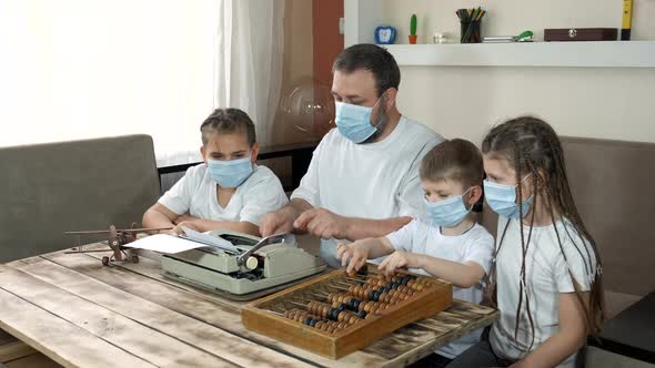 Dad Shows the Children in Medical Masks an Old Typewriter and Bills. Social Distancing and Self