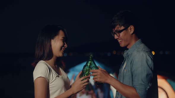 Couple Asian teenagers drinking have fun salute toast of bottle beer enjoy party at night.