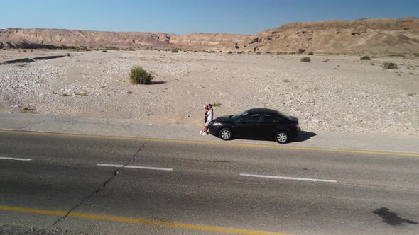 Aerial Shot of Couple Hugging and Kissing While Standing Near the Car While Traveling Outdoors