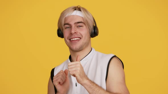 Young Active Guy Listening to Music in Wireless Headphones and Dancing Smiling and Flirting to alt