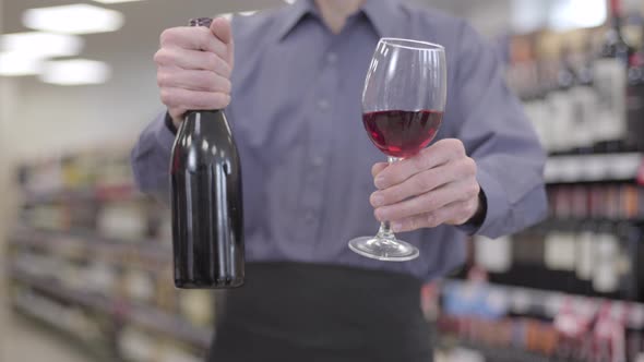 Unknown Adult Caucasian Man Stretching Bottle and Glass of Red Wine To Camera. Unrecognizable alt