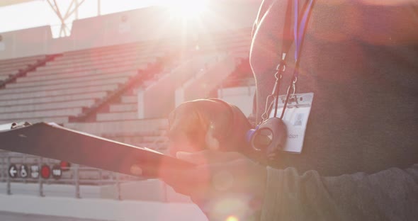Midsection of african american male coach time cheking and making notes alt
