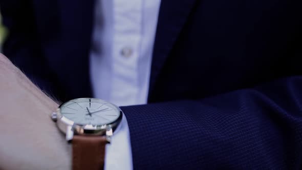 a man in a blue suit puts on a wristwatch