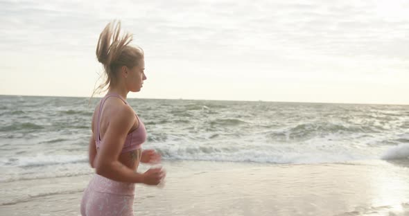 Woman in Sportswear Goes Jogging Along Embankment By Sea alt