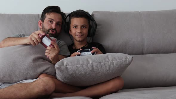 Father and Young Child are Playing Video Game on Couch at Home