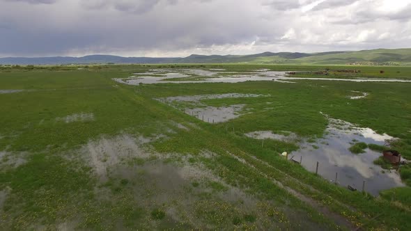 Aerial view flying over flooded field next to river during spring runoff alt