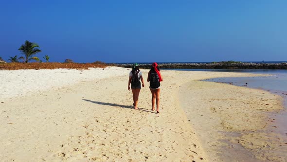 Women happy together on tranquil coastline beach journey by blue lagoon with white sand background o alt