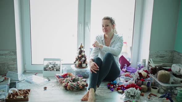 Girl is Sitting By Window Around Her Scattered for Christmas Decorations
