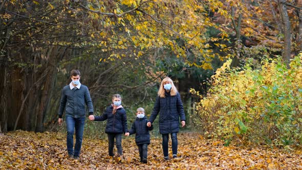 Family, parents with children in medical masks walk in the Park on an autumn day.