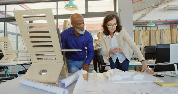 Business executives discussing over architectural model 4k alt