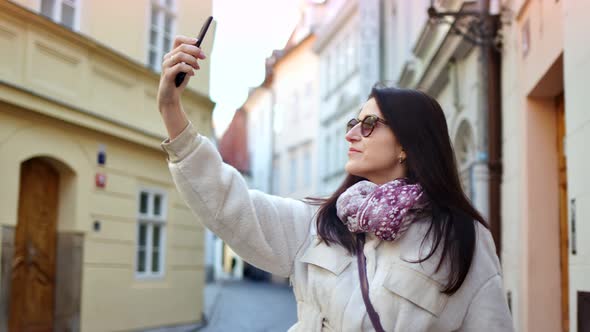 Smiling Female Tourist Taking Selfie Using Smartphone Posing Surrounded By Historical Architecture alt