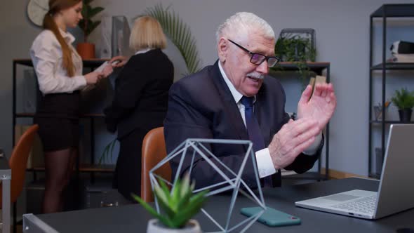 Cunning Senior Businessman Rubbing Hands Scheming Evil Tricky Prank Plan in Mind in Office Interior alt