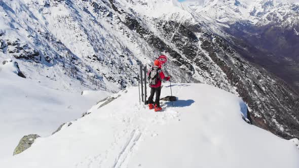 AERIAL: Hiker on mountain top, ski touring mountaineering snow mountain, panoramic view on the alps alt