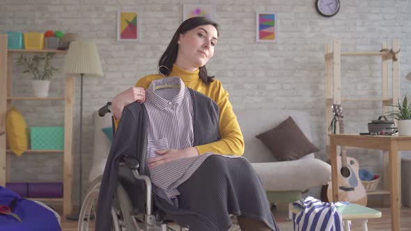 Young Disabled Girl in a Wheelchair Is Going on a Date Trying on Clothes alt