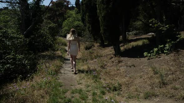 A Woman in a White Short Dress Runs Down the Path From the Mountain By the Tall