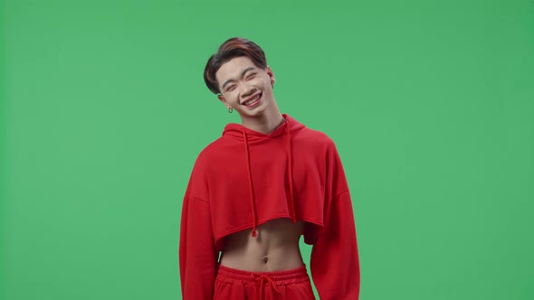 Jealous Young Asian Transgender Male Smiling While Standing In The Green Screen Studio alt