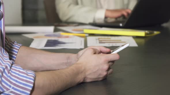 Cropped Close Up of a Businessman Typing on His Smart Phone at the Office alt
