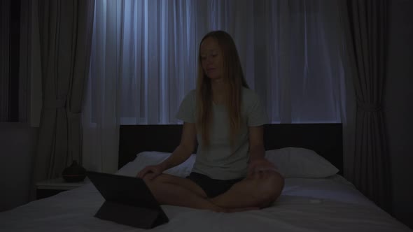 A Woman at Night Turns on a Meditation Relaxation Application on Her Tablet to Relax Before Going to alt