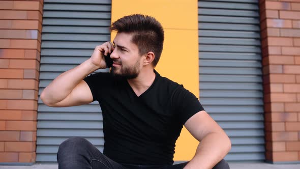 Portrait of a Charismatic Young Man Talking on the Phone While Waiting for Public Transport. alt