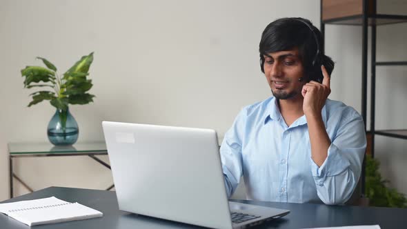 Smiling Indian Male Office Employee Wearing Headset Talking Online