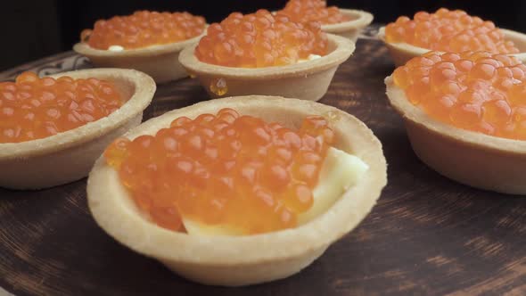Red Caviar Is Put with a Spoon on Tartlets. Preparation of Snacks with Red Caviar. Top View
