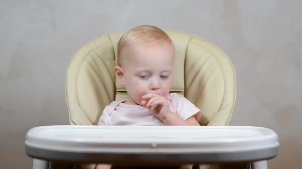little girl misses in the feeding chair, waiting for feeding alt