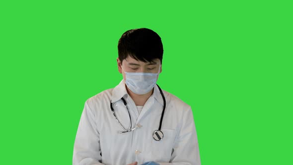 Young Asian Doctor Walks Taking Off Gloves and Mask on a Green Screen Chroma Key
