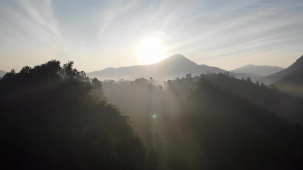 Aerial clip of beautiful sunrise behind a mountain valley in the morning with rays of sunlight