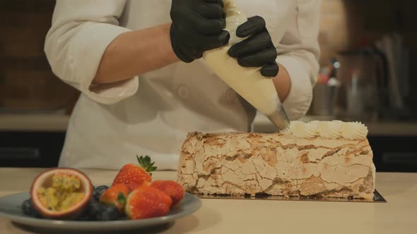 a Woman Pastry Chef Squeezes Butter Cream Out of a Cooler Onto a Meringue Roll
